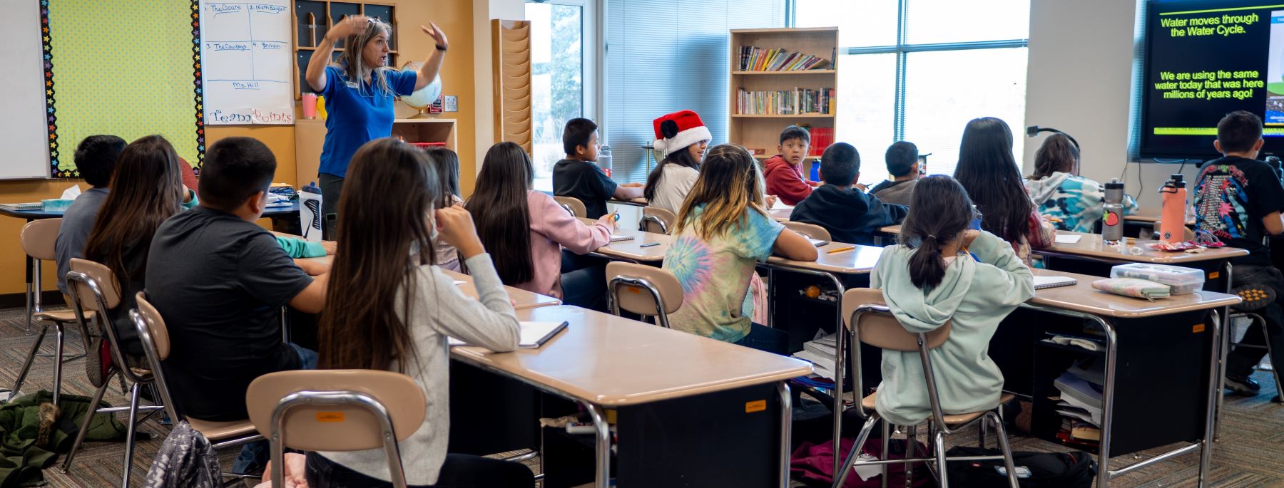 Teacher conducting a class full of students on water cycle.