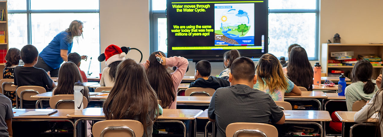 Full classroom of children with female teacher at the front of the class. 