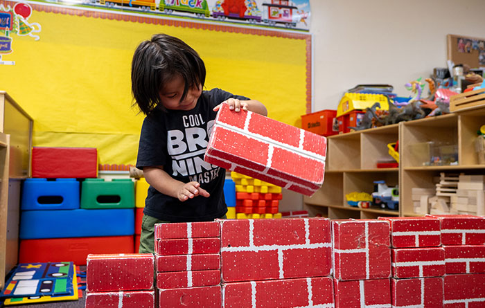 Young male kindergartener playing with red blocks.